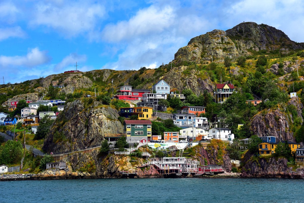 Colorful houses perched on a rocky cliff by the sea under blue sky.