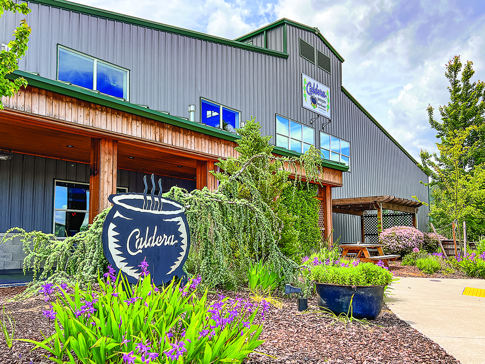 Image of grey exterior of a brewery with small garden in front.