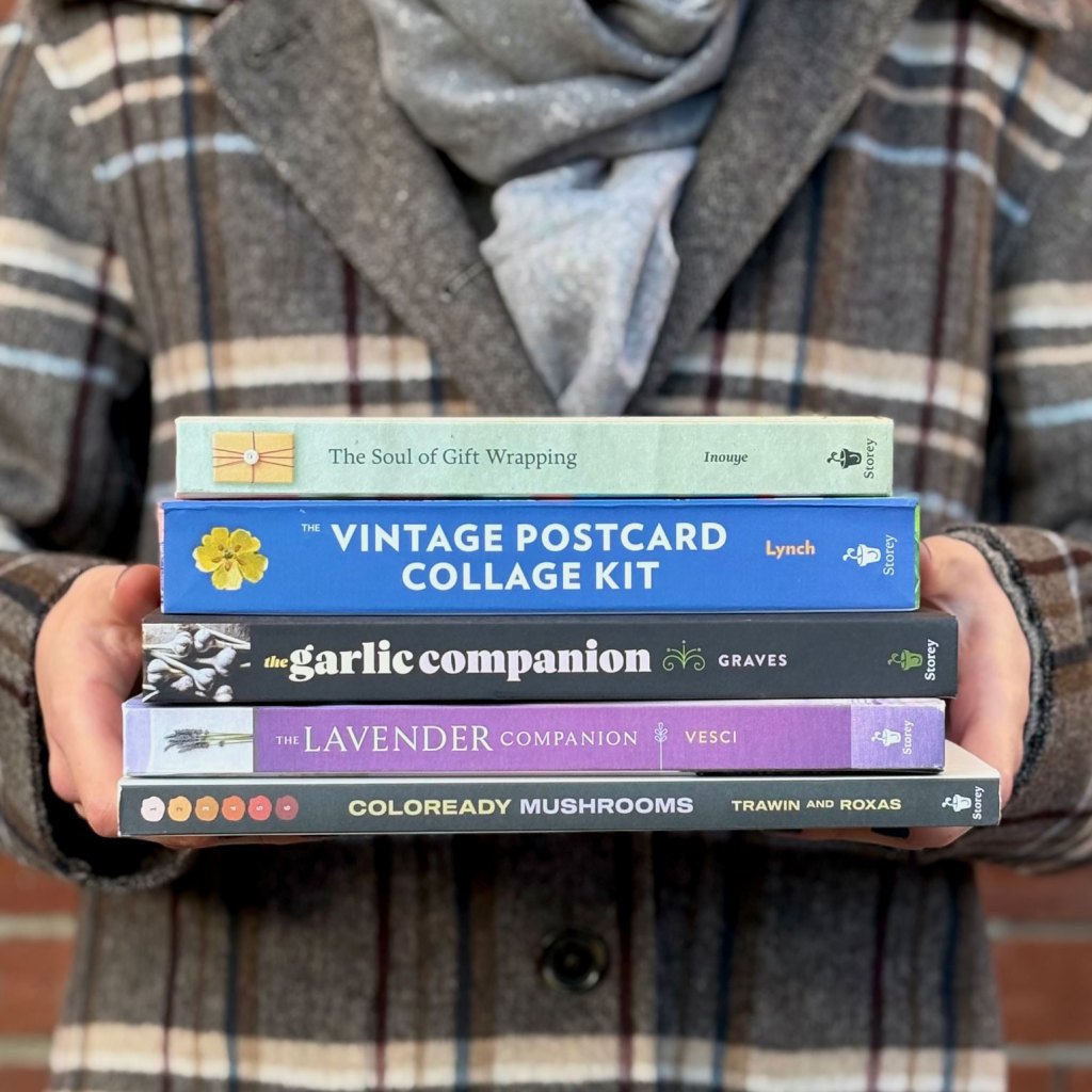 Person holding stack of craft books. 