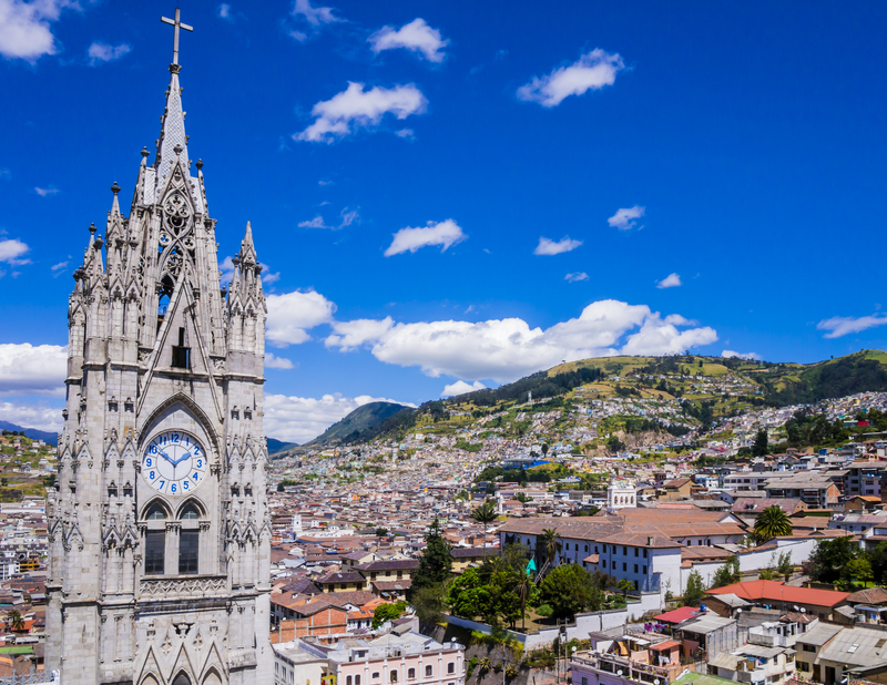 Image of city under bright blue sky with a church tower in the foreground.