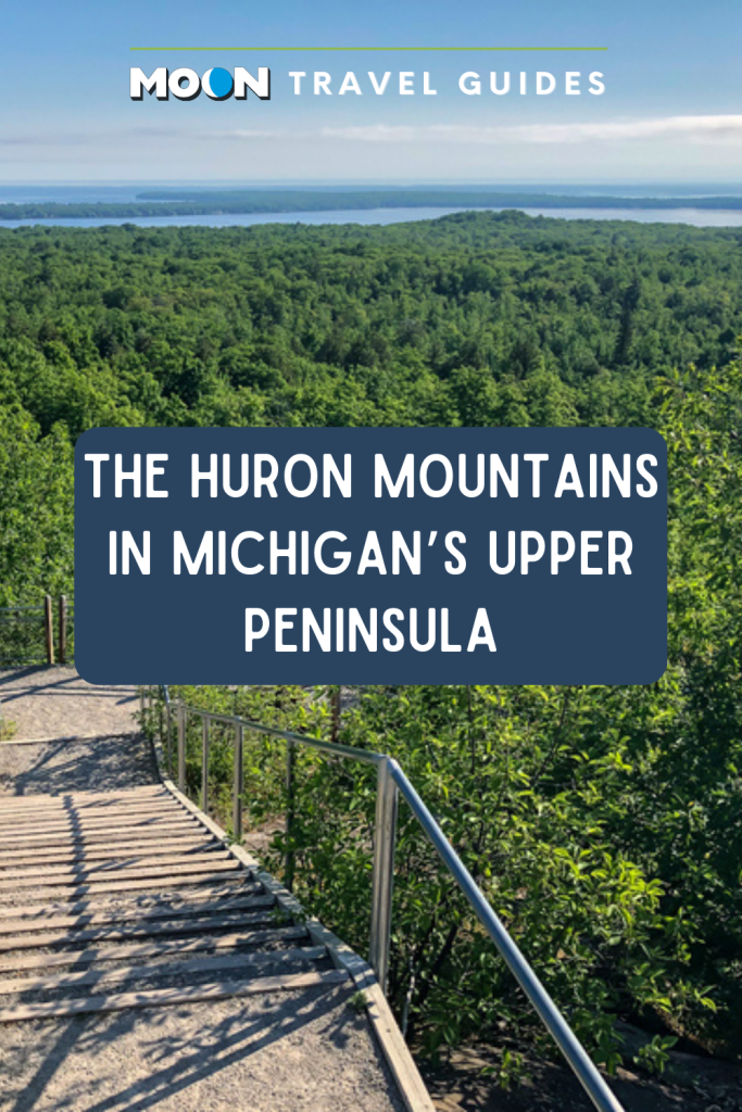 Image of trail leading down into forested mountains with text the Huron Mountains in Michigan's Upper Peninsula