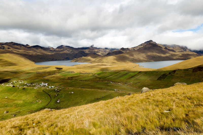 Image of two lakes in a lush yellow-green mountain valley under cloudy grey skies.