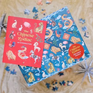 Photo of “The Chinese Zodiac 500-Piece Puzzle” box, included mini book, and scattered puzzle pieces