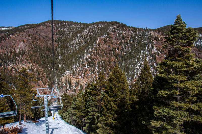 Image of ski lift leading into forested valley with dusting of snow.