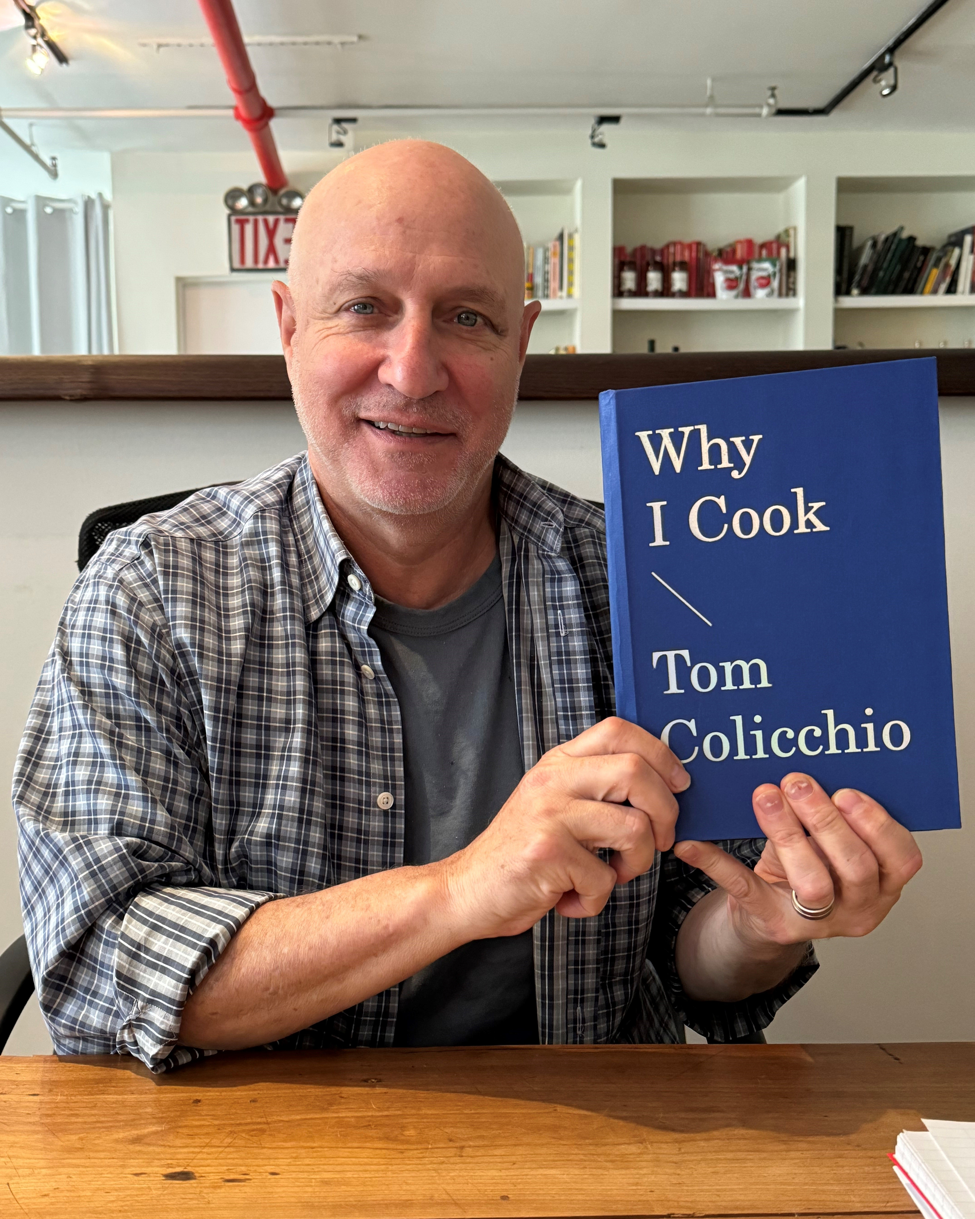 Tom Colicchio holding a copy of his book, Why I Cook