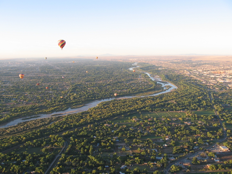 Hot air balloons over landscape with river and green trees