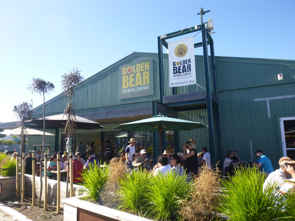 Image of exterior of a brewery with people sitting at tables outside.