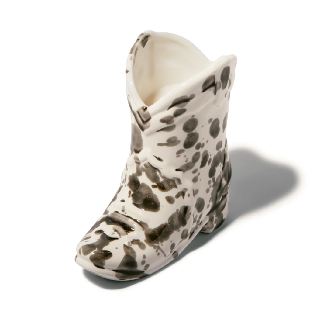 Image of a cowboy boot-shaped ceramic candle with black cow print spots