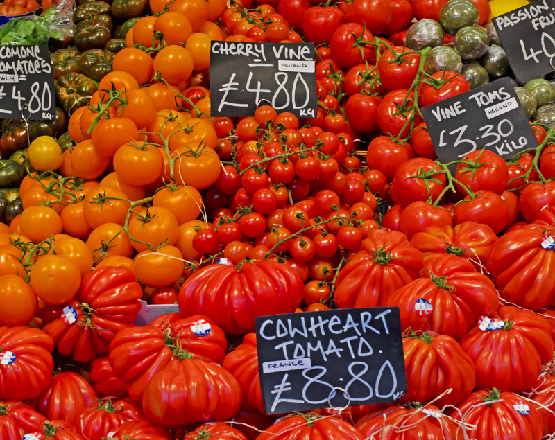 A table heaped with piles of different varieties of tomatoes.