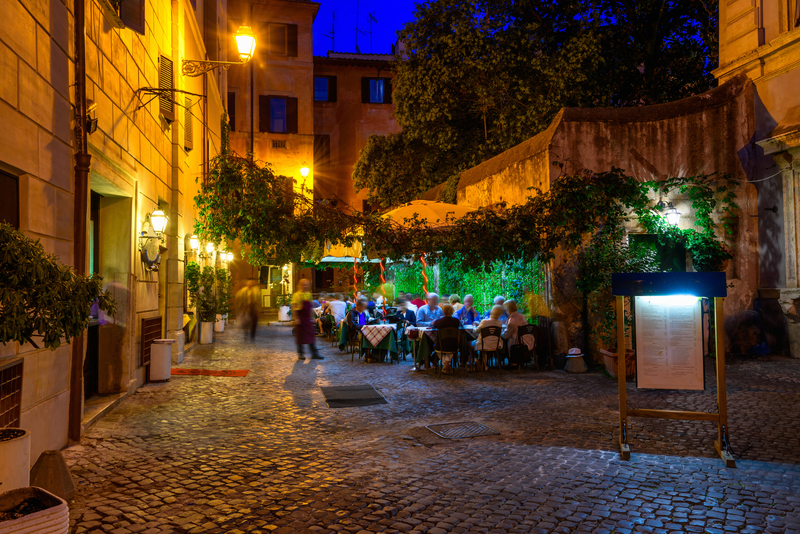 Image of cobblestone street with diners eating outdoors at night