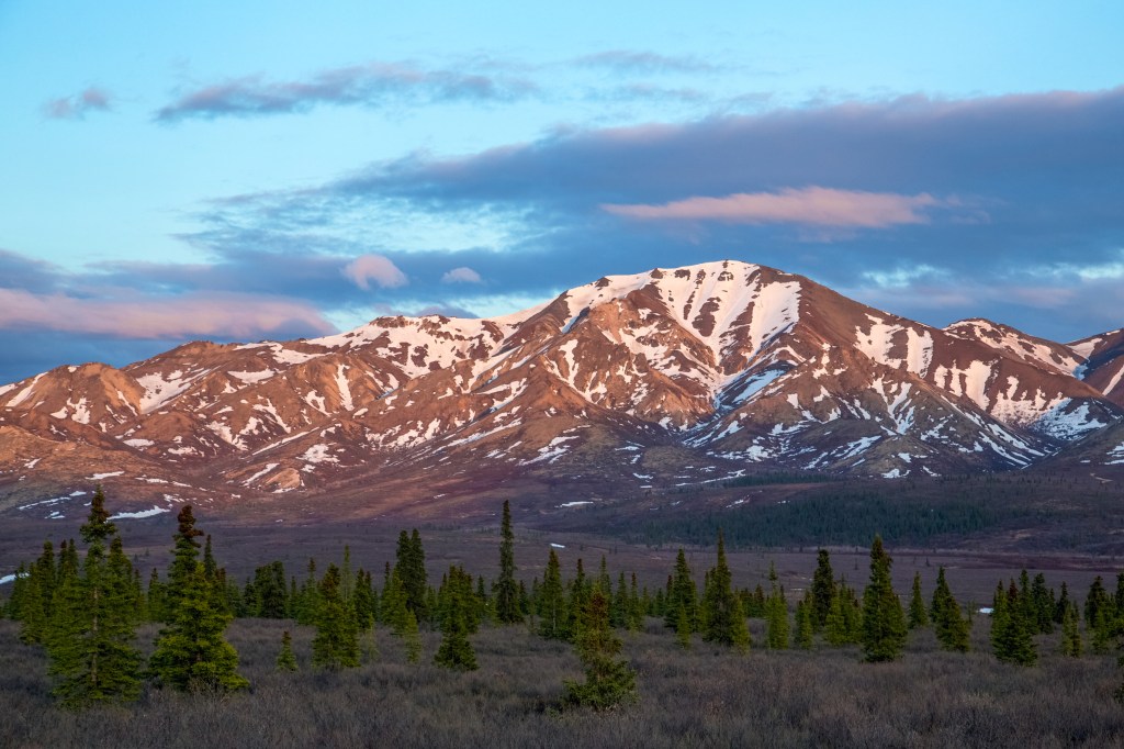 Snow-covered mountains and tundra illuminated by softly glowing light